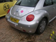 a silver car with flowers painted on it's rear end and bumper stickers