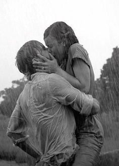 two people are hugging in the rain with one person holding his arm around the other