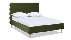 a green bed with two pillows on top of it and an open headboard to the side