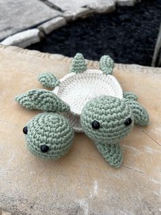 a crocheted turtle laying on top of a rock