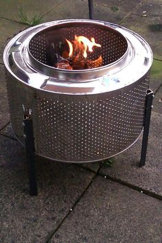 a metal fire pit sitting on top of a sidewalk