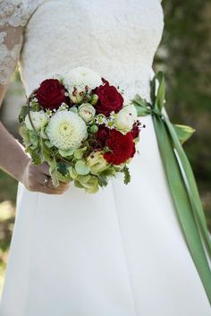 a bride holding a bouquet of red and white flowers