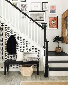 a staircase with black and white wallpaper, pictures on the wall and a bench