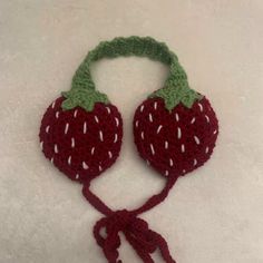 a crocheted strawberries headband and ear muffs on a white surface