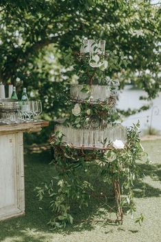 a table topped with a cake covered in flowers and greenery next to a tree