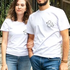 Find the perfect romantic gift with our Personalized Couples Initial T-Shirt Set, ideal for Valentine's Day, birthdays, or New Year's Eve celebrations. Celebrate love with matching style!Celebrate your unique connection with the Personalized Couples Initial T-Shirt Set, a romantic and thoughtful gift designed to bring couples closer together. This personalized apparel is not just a gift; it's a wearable testament to the bond you share with your partner, making it perfect for occasions like Valen Crew Neck T-shirt For Anniversary In Summer, Anniversary Letter Print T-shirt For Summer, Summer Anniversary T-shirt With Letter Print, Cotton Tops For Summer Anniversary, Summer Cotton Tops For Anniversary, Cotton Tops For Anniversary In Summer, White Valentine's Day T-shirt With Text Print, White Graphic Print Top For Anniversary, Fitted Short Sleeve Tops For Anniversary