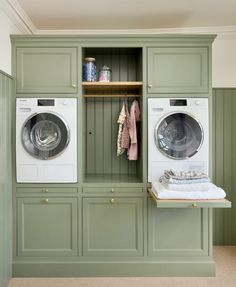 a washer and dryer in a room with green cabinets on the wall, next to each other