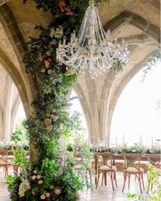 an indoor wedding venue with chandelier and greenery