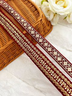 two red and gold trims sitting on top of a basket next to white flowers