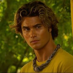 a close up of a person wearing a yellow shirt and a snake around his neck