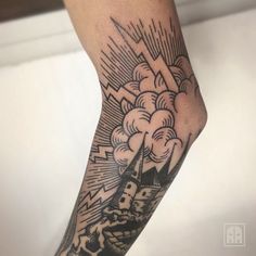 a man's arm with a lighthouse and clouds tattoo on the left side of his leg