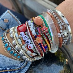 a woman's arm with bracelets and charms on it, all stacked together