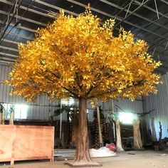 a large yellow tree with lots of leaves on it's trunk in a warehouse