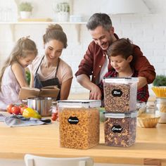 three people and two children are looking at food in containers on the kitchen counter top