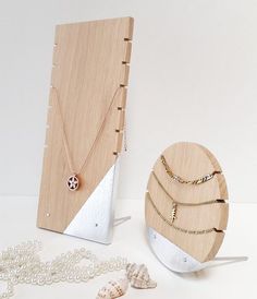 three necklaces are on display in front of a wooden card holder with two other jewelry pieces