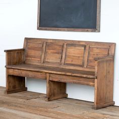 an old wooden bench sitting in front of a chalkboard on the side of a wall