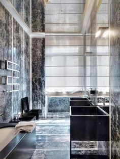 a bathroom with marble walls and flooring next to a bathtub in the middle