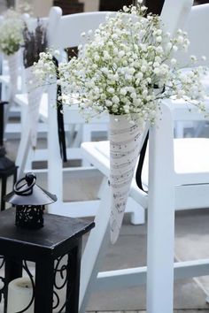 a bunch of white flowers sitting in a vase on top of a table next to some chairs