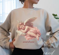 a woman wearing a sweatshirt with an angel on the back and words sweet dreams printed on it