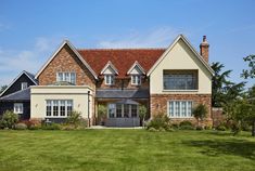 a large brick house with white trim and windows on the front, surrounded by lush green grass