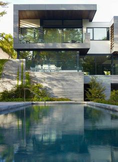 an outdoor swimming pool in front of a modern house