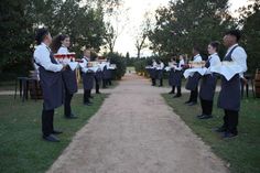 a group of men standing on top of a dirt road holding trays of food