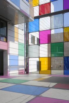 an empty room with multicolored walls and floor tiles on the ground, in front of a building