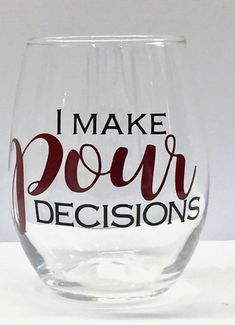 a wine glass with the words i make pour decisions printed on it, sitting on a white surface