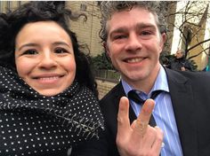 a man standing next to a woman giving the peace sign