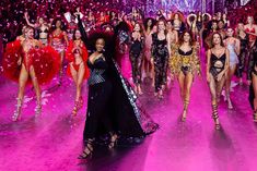 several models walk down the runway with pink and purple confetti in the background