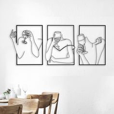 three black and white drawings hanging on the wall above a dining room table with chairs