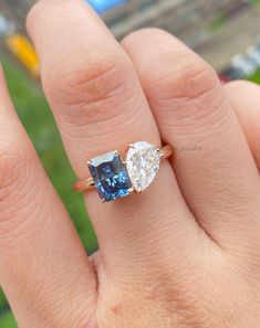 a woman's hand holding an engagement ring with two blue and white stones