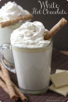 two mugs filled with whipped cream and cinnamon stick garnished in white chocolate