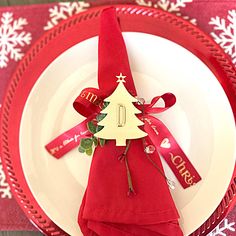 a red and white place setting with a christmas tree napkin holder on top of it