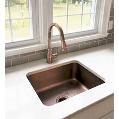 a kitchen sink with a faucet in front of a window that is open