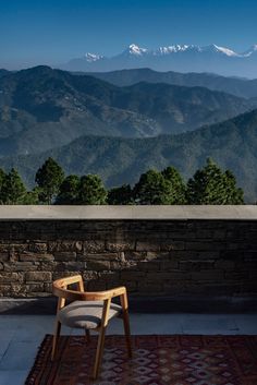 a chair sitting on top of a rug next to a stone wall and mountain range