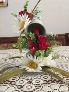 a vase filled with red roses and white daisies sitting on top of a table