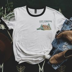 a white t - shirt with the words camp crown on it next to jeans and shoes