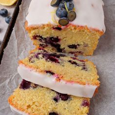 two slices of cake with white frosting and blueberries on top, sitting next to some sliced lemons