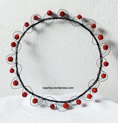 a circle made out of wire with red balls on it's ends and stringing around the edges