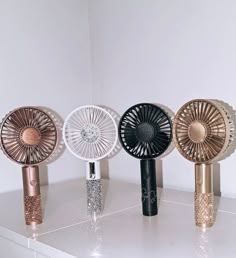 three different types of decorative fans sitting on a white countertop next to each other