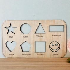 a wooden frame with different shapes and sizes on top of a table next to a pink flower