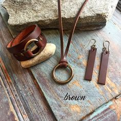 a pair of brown leather bracelets sitting on top of a rock