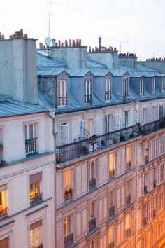 an apartment building with lots of windows and balconies at dusk, in paris