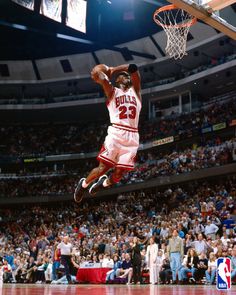 a basketball player jumping up into the air to dunk a ball in front of an audience