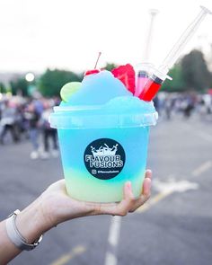 a person holding up a blue and green drink with straws in it's cup