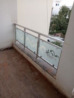 an empty balcony with glass railings and wood flooring