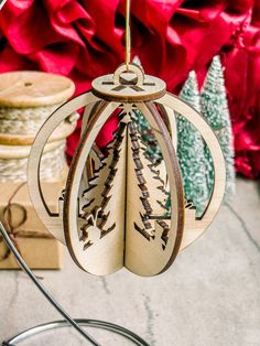 a wooden ornament hanging from a wire with red flowers in the back ground