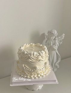 a white wedding cake with angel figurines on top