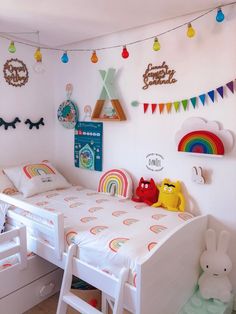 a child's bedroom with white furniture and rainbow decorations on the wall above the bed